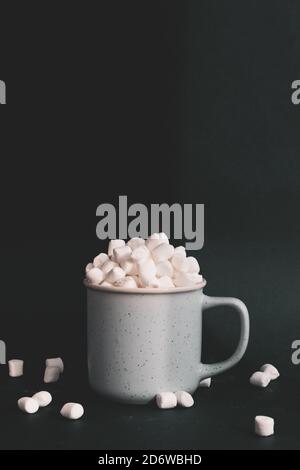 Marshmallows in einer Tasse vor dunkelblauem Hintergrund, Bild mit geringem Kontrast Stockfoto