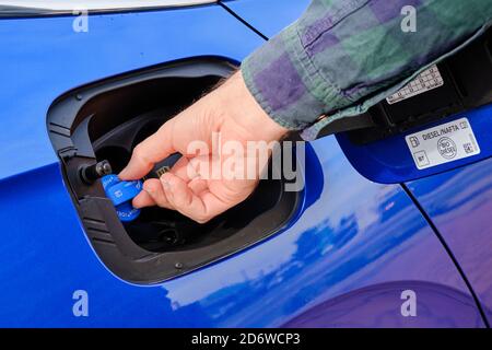 Nahaufnahme mans Hand öffnet einen Tank für Ad Blue Flüssigkeit eines blauen Autos. Diesel-Abgasflüssigkeit oder DEF zur Verringerung der Luftverschmutzung, Oktober 2020, Prag Stockfoto
