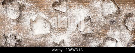 Weihnachtsbanner mit Plätzchen-Formen und Mehl auf Holzhintergrund. Stockfoto