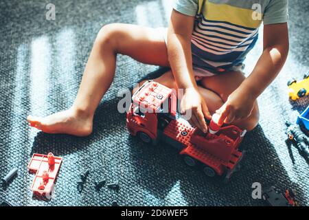 Foto von oben von einem Jungen, der auf dem Boden sitzt Und bauen ein Auto von Konstruktor Stockfoto