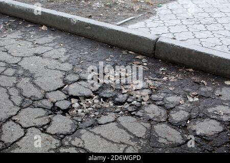 Gebrochener Asphalt. Gebrochene Straßenoberfläche im Innenhof eines Wohngebietes. Stockfoto