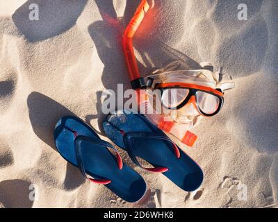 Schwimmmaske und Flip-Flops auf Sandhintergrund Stockfoto