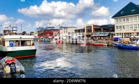 Geschäfte, Boote und Cafés am Alten Strom Canal in der Nähe der Hafen im Zentrum von Warnemünde, in der Nähe von Rostock an der Küste im Norden von Deutschland. Stockfoto