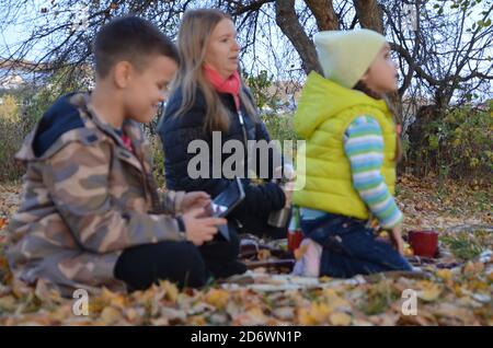 Glückliche Familie auf Herbst-Picknick im Park Mama mit Sohn Und die Tochter im Park oder im Wald sitzen auf einem Decke Stockfoto