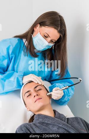 Mikrodermabrasion des Gesichts, eine Technik, die abgestorbene Zellen und Verunreinigungen aus der Epidermis beseitigt, Peeling der Oberflächenschicht der Haut, C Stockfoto