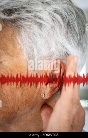 Nahaufnahme des Ohrs einer Frau, mit Grafiken, die Schallwellen darstellen. Stockfoto