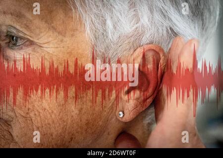 Nahaufnahme des Ohrs einer Frau, mit Grafiken, die Schallwellen darstellen. Stockfoto