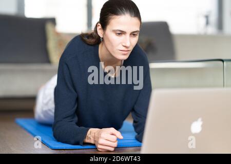 Frau praktiziert Yoga online am Laptop zu Hause. Stockfoto