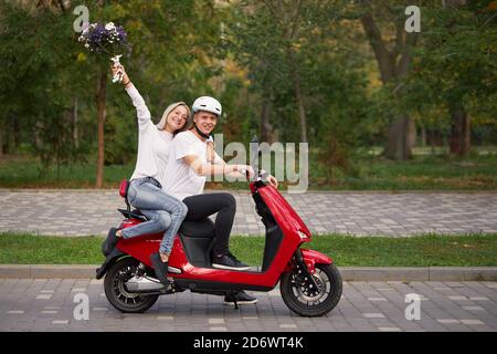 Glücklich junge Liebe Paar auf Retro roten Roller im Freien. Romantische Datierung im Park Stockfoto