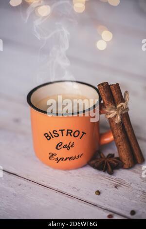 Vintage orange Kaffeetasse mit Zimt und Sternanis auf weißem Holzhintergrund. Gemütliches Hauskonzept Stockfoto