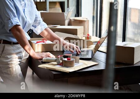 Weibliche Online-Geschäft Eigentümer Verpackung Versand eCommerce Paket mit Laptop. Stockfoto