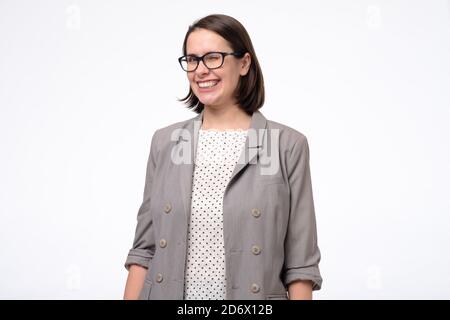 Reife Frau winkend lächelnd, während sie vor grauem Hintergrund steht Stockfoto