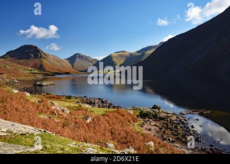 Wast Water oder Wastwater Lake im Lake District National Park, England. Herbstfarben auf den Bergen und Laub. Sonnenposition wirft einen Schatten. Stockfoto