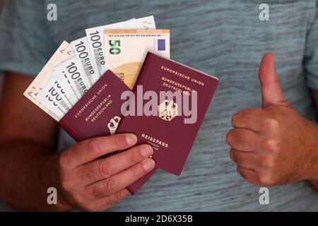 Selektive Fokusaufnahme eines Mannes mit zwei neuen deutschen Pässe und Geld in den Händen Stockfoto