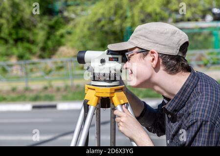 Samara, Russland - 12. Juni 2019: Vermessungsingenieur Arbeiter, die Messungen mit geodätischen optischen Ebene.topographische Untersuchung. Geodätische Werke Stockfoto