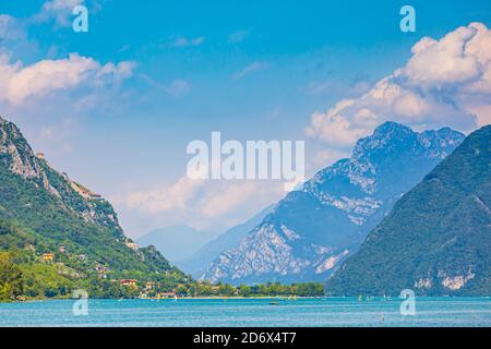 Schöner Blick über den Idrosee Italien. Häuser, ein kleines Dorf auf der Vorder- und blaues Wasser und Berge im Hintergrund. Stockfoto