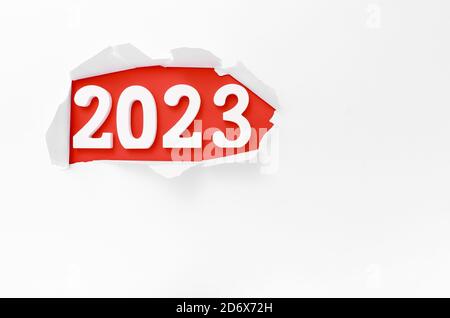 '2023' geschrieben hinter einem zerrissenen weißen Papier auf einem roten Hintergrund Stockfoto