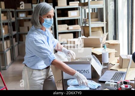 Reife weibliche Freiwillige tragen Maske Verpackung medizinische Spenden Box. Stockfoto