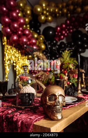 Halloween-Tisch mit einigen gruseligen Ornamenten, wie einem Totenkopf, einer schwarzen Fledermaus oder einem geschnitzten Kürbis geschmückt. Halloween Stillleben Dekoration. Weihnachtsdekoration. Stockfoto