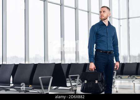 Geschäftsmann, der in der Wartelounge am Flughafen sitzt und auf den Flug wartet. Männlicher Manager in der Business Lounge des Flughafens, der im Wartebereich sitzt. Stockfoto