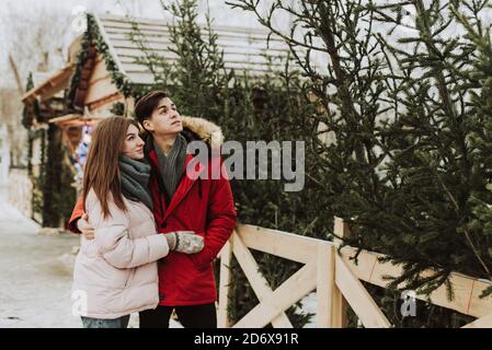 Ein junges Paar kauft einen Weihnachtsbaum auf dem Markt in ihrem Haus. Konzept - ein Symbol für Weihnachten und Neujahr. Stockfoto