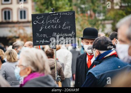 Straßburg, Frankreich - 19. Oktober 2020: Mann als alter Lehrer gekleidet mit Plakat an Ort und Stelle Kleber zu Ehren des Geschichtslehrers Samuel Paty zu zahlen, enthauptet am 16. Oktober nach der Vorführung von Karikaturen Stockfoto