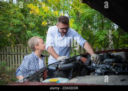 Junger Vater Lehre seinen Sohn Motoröl in Familie Auto zu ändern. Stockfoto