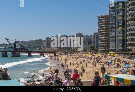 Vina Del Mar, Chile - 8. Dezember 2008: Sandstrand voller Menschen und bunten Sonnenschirmen mit Wand von hohen Luxus-Wohnhäusern in der Rückseite unter b Stockfoto