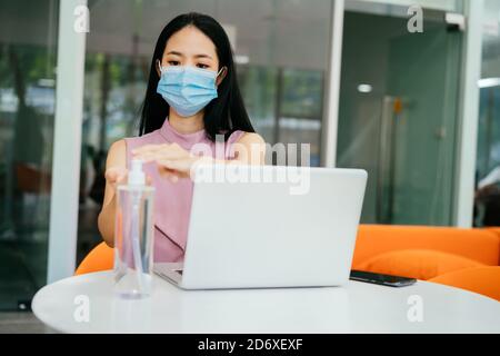 Asiatische Geschäftsfrau tragen schützende Covid Gesichtsbedeckung arbeiten in modernen Büro, mit Computer, Konzentration, Schutz, Gesundheit Stockfoto