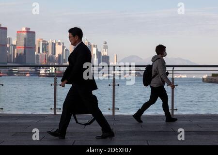 Ein Geschäftsmann und eine Frau gehen vor die Skyline von Hongkong, China. Stockfoto