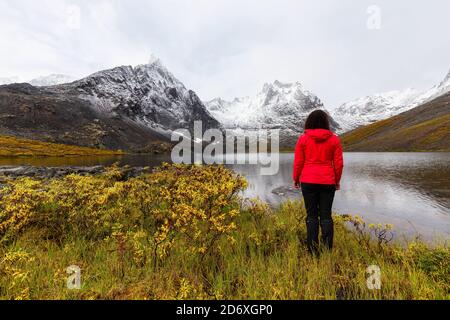 Frau, die am wunderschönen Alpinen See steht, umgeben von Snowy Mountains Stockfoto