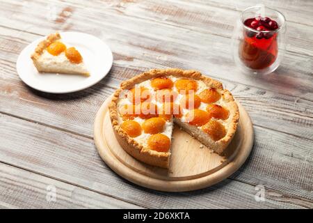 Hausgemachter Pfirsich-Käsekuchen, Beerentee-Tasse, Stück Kuchen in der Nähe auf dem Teller Stockfoto