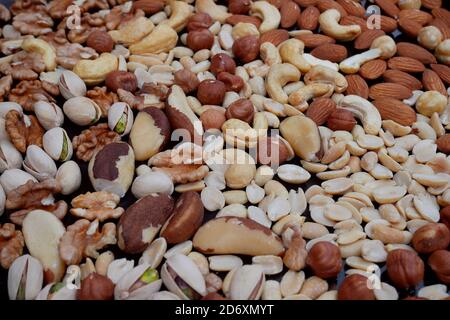 Viele verschiedene Nüsse auf dunkelblauem Metalldeck: Erdnüsse, Cashewkerne, Haselnüsse, Paranüsse, Mandeln, Pistazien, Walnüsse, Popularität als beste des Menschen, in der Nähe Stockfoto