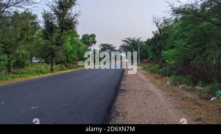 18. Oktober 2020 : Reengus, Jaipur, Indien / schöne Aussicht durch die leere Straße am Morgen erstellt. Leere Straße, die zum Dorf und White Clouds führt Stockfoto