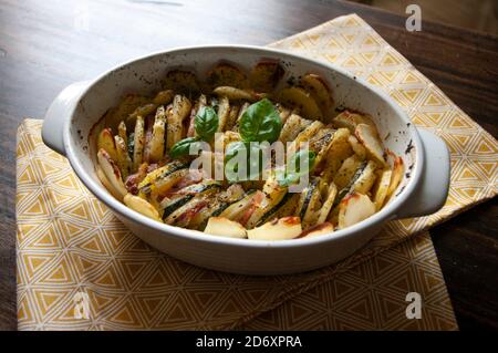 Herzhafte Kartoffelgratin Speck und Zucchini, frisch aus dem Ofen auf einem Holztisch serviert.Keramik-Auflauf. Stockfoto