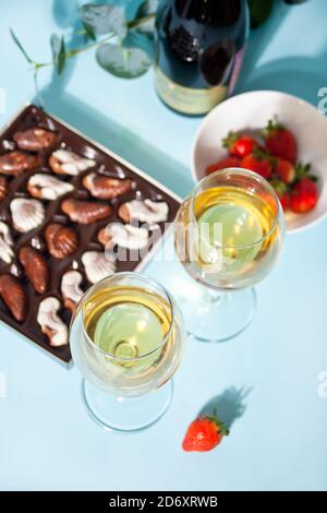 Gläser mit Champagner oder Wein. Schachtel Pralinen, Erdbeeren und Flasche auf dem Hintergrund Stockfoto