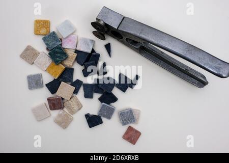 Bunte kleine Marmorsteine in quadratischer Form mit besonderen Zange für Mosaikarbeiten Stockfoto