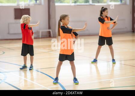 Drei Kinder trainieren im Fitnessstudio und biegen nach links ab Stockfoto