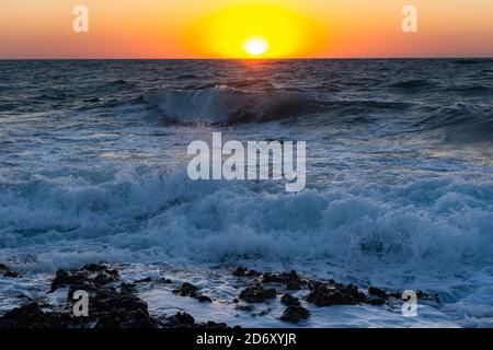 Sonnenuntergang und Sturm auf dem Meer. Große Wellen gegen die untergehende Sonne. Sommersturm auf dem Schwarzen Meer. Schönes Meeresspray mit Schaumbrüchen an der felsigen Küste. Be Stockfoto