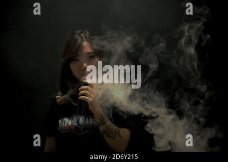 Portrait der Woman Vape Cloud Performerin Deborah Chen, nachdem sie an einem Vape Cloud Trick Contest teilgenommen hat, der während des jährlichen Vape Fest in Jakarta, Indonesien, stattfand. Deborahs Erfahrung mit dem Verdampfen begann mit einer Behandlung von Lungenentzündung und einem grünen Licht von ihrem Arzt. "Ich hatte eine Lungenentzündung in der Geschichte, benutzte Shisha-Technik als Teil meiner Behandlung. Ich fragte meinen Arzt, ob ich zu einer E-Zigarette wechseln könnte. Er sagte, es sei in Ordnung“, sagt sie. Stockfoto