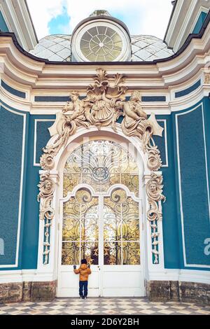 Zarskoje Selo, Puschkin, Sankt Petersburg, Russland - 10.07.2020 : kleiner Junge, der in die Glastür des Grotto-Pavillons im Katharinapark schaut Stockfoto