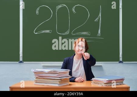 Ein Lehrer zeigt einen Finger nach vorne auf eine Tafel mit dem Text 2021. Probleme der Schulbildung und des Internetunterrichts im Coronavirus-Quaran Stockfoto