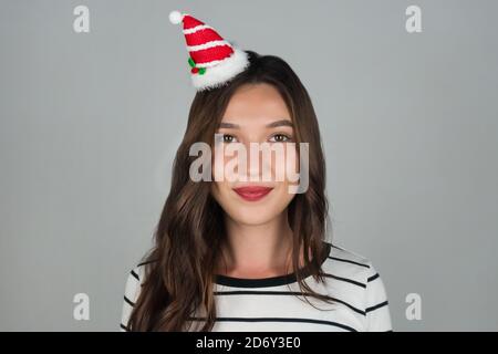 Eine glückliche junge Frau mit Weihnachtsdekoration im Haar schaut in die Kamera. Weihnachten und Neujahr feiern. Hochwertige Fotos Stockfoto