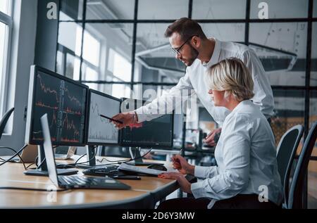 Gemeinsame Analyse von Informationen. Zwei Börsenmakler in formeller Kleidung arbeiten im Büro mit dem Finanzmarkt Stockfoto