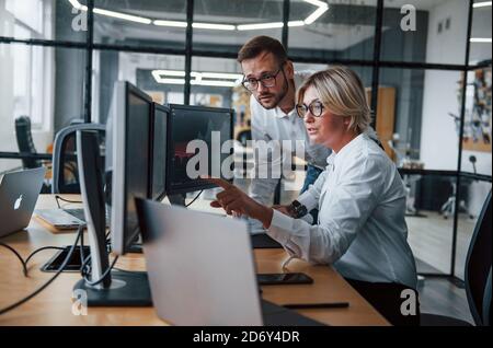 Zwei Börsenmakler in formeller Kleidung arbeiten im Büro mit Finanzmarkt Stockfoto