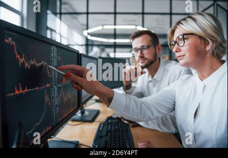 Legt den Stift auf das Display. Zwei Börsenmakler in formeller Kleidung arbeiten im Büro mit dem Finanzmarkt Stockfoto