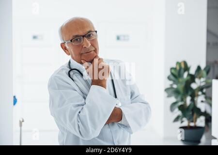 Porträt eines älteren Arztes in weißer Uniform, die in steht Die Klinik Stockfoto