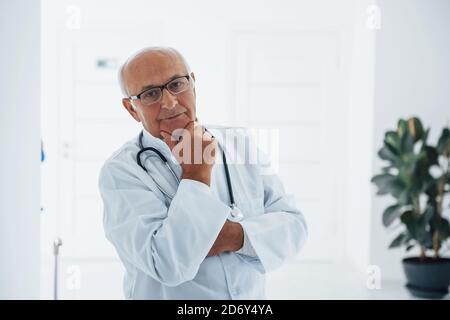 Porträt eines älteren Arztes in weißer Uniform, die in steht Die Klinik Stockfoto