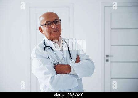 Porträt eines älteren Arztes in weißer Uniform, die in steht Die Klinik Stockfoto