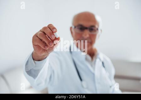 Porträt von Senior Doktor weiße Uniform, die in der steht Klinik mit Pille in der Hand Stockfoto